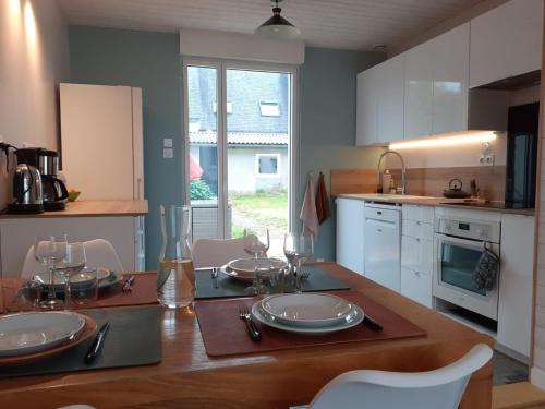 une cuisine avec une table avec des assiettes et des verres dessus dans l'établissement Maison au calme idéale pour découvrir Sud Finistère, à Quimper
