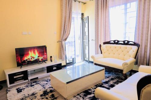Una sala de estar con un sofá y un televisor. en Comfort Luxury Apartments, en Kampala