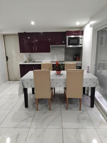 une cuisine avec une table et des chaises dans une cuisine dans l'établissement Appartement au calme, à Chantepie