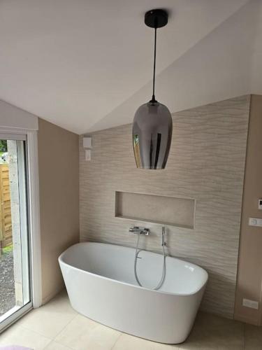 a white bath tub in a bathroom with a pendant light at À L'ombre Du Pêcher in Pleurtuit