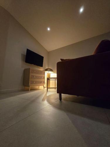 a living room with a couch and a tv at À L'ombre Du Pêcher in Pleurtuit