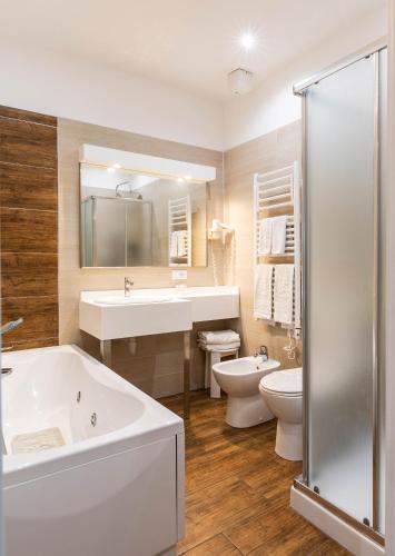 a bathroom with a tub and a sink and a toilet at Hotel Lungomare in Marina di Andora