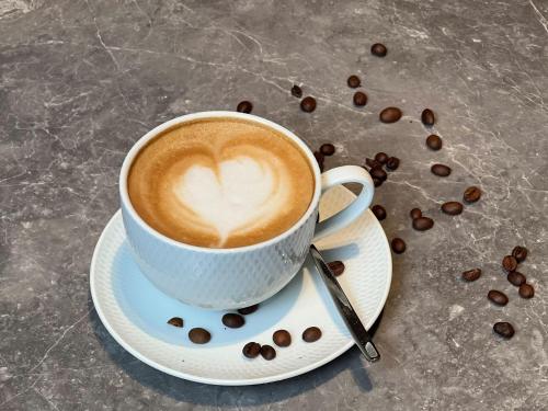 a cup of coffee on a plate with coffee beans at Doubletree By Hilton Rugao in Rugao