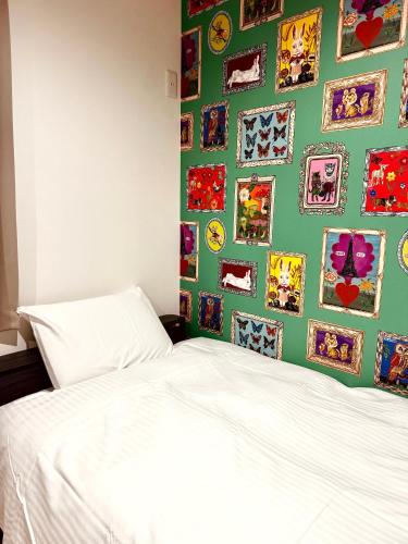 a bedroom with a white bed and a green wall with pictures at Niseko Purr 101 in Kutchan