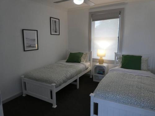 a white room with two beds and a window at Moonta Bay Stylish large home 3 min walk from beach and jetty in Port Moonta