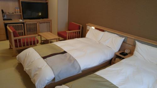 um quarto de hotel com duas camas e uma televisão em Onyado Nono em Sakaiminato