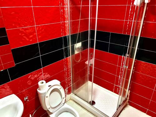 a red tiled bathroom with a toilet and a sink at Hostal Gracias in Madrid