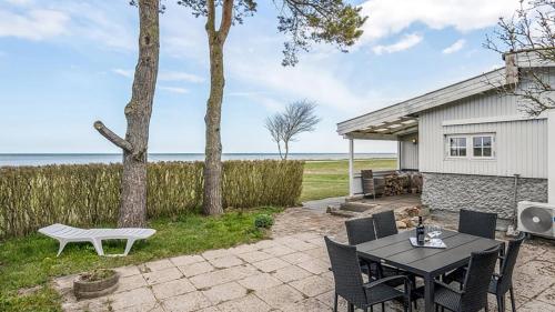 a patio with a table and chairs in front of a house at Djursland Lystrup Strand Ferieboliger in Allingåbro