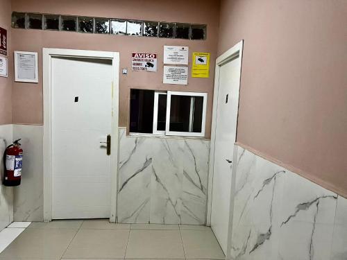 two white doors in a room with a marble wall at Hostal Gracias in Madrid