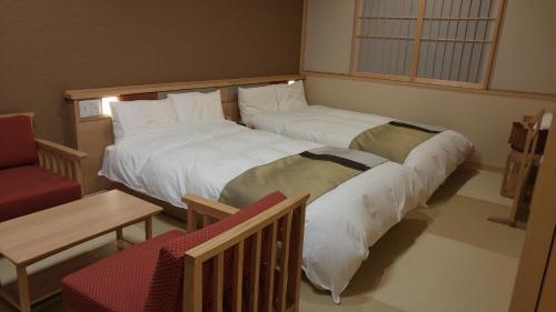 two large beds in a room with a chair at Onyado Nono Sakaiminato Natural Hot Spring in Sakaiminato