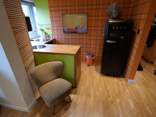 a kitchen with a black refrigerator and a chair at 2 Zimmer-Apartment im Schanzenviertel, 41qm in Hamburg
