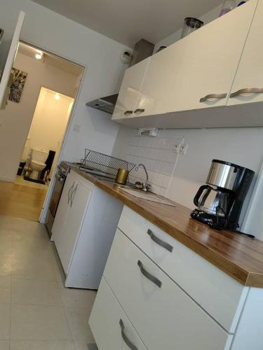 une cuisine avec des armoires blanches et un comptoir dans l'établissement Les Lilas, à Chantepie