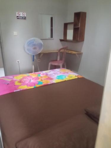 a bedroom with a bed with a flower blanket on it at Surya homestay in Batukaras