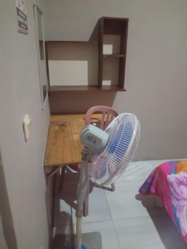 a fan sitting on a chair next to a table at Surya homestay in Batukaras