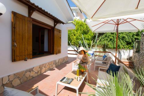a woman sitting on the patio of a house at Appartamento in Villa con Terrazzo e Vista Golfo in Massa Lubrense