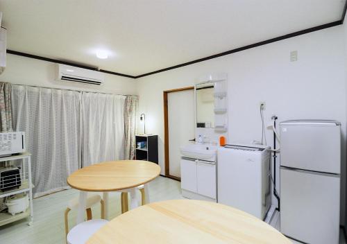 a small kitchen with a table and a refrigerator at GLOCE 南伊豆アウトドアベースキャンプ（ゲストハウス） in Minamiizu