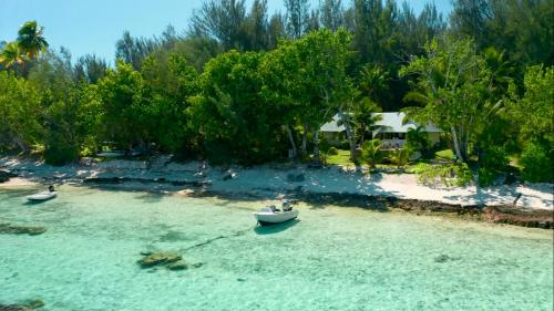 two boats in the water on a beach at Fare One Island Moorea in Haapiti