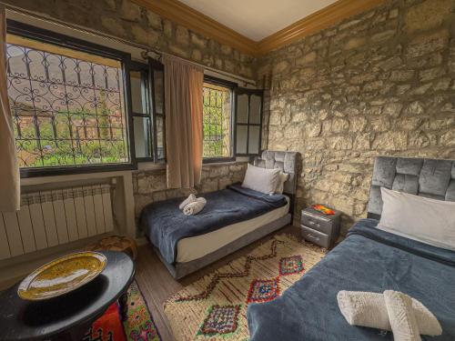 a bedroom with two beds and a stone wall at Tonaroz House in Imlil