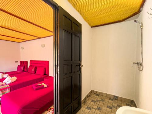 a bedroom with a red bed and a shower at Tonaroz House in Imlil