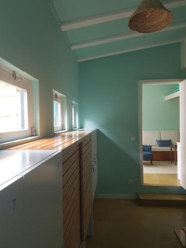 a kitchen with blue walls and white cabinets and a mirror at Conde Surf Camp - Capsule Beds FEMALE Dorm in Vila do Conde