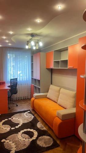 a living room with an orange couch and a desk at Bella space in Suceava