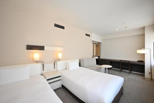 a hotel room with two beds and a couch at Hotel Keihan Tokyo Yotsuya in Tokyo