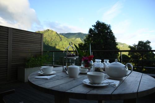 a wooden table with a tea set on a balcony at Taj Chia Kutir Resort & Spa Darjeeling in Darjeeling