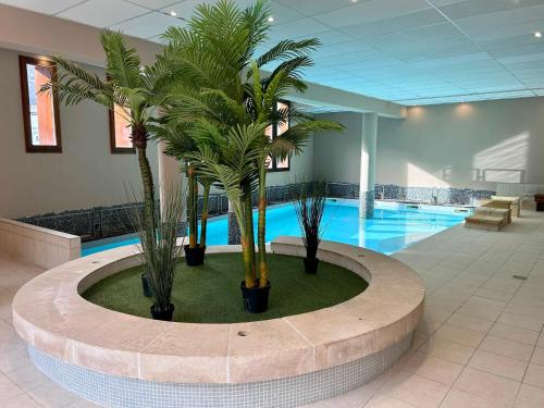 a lobby with a pool with palm trees in it at Le Rioumajou 1 - Grand T6 - Piscine - Centre St Lary in Saint-Lary-Soulan