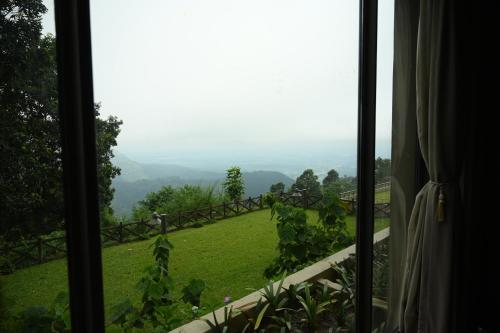 a window with a view of a green field at Taj Chia Kutir Resort & Spa Darjeeling in Darjeeling