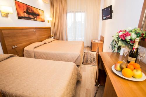 a hotel room with two beds and a plate of fruit on a table at Pefka Hotel in Thessaloniki