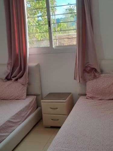a small bedroom with two beds and a window at Marwan's apartment 2 in Ifrane