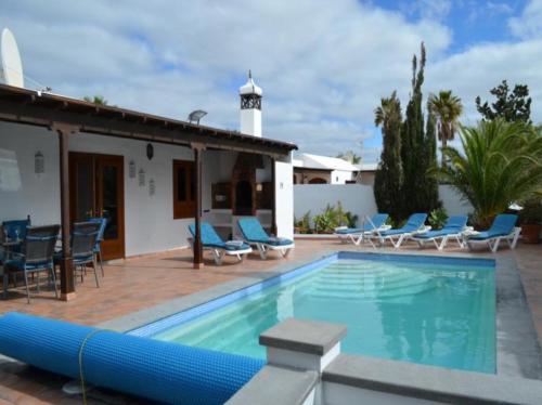 a swimming pool with chairs and a house at Casa Terria in Tías