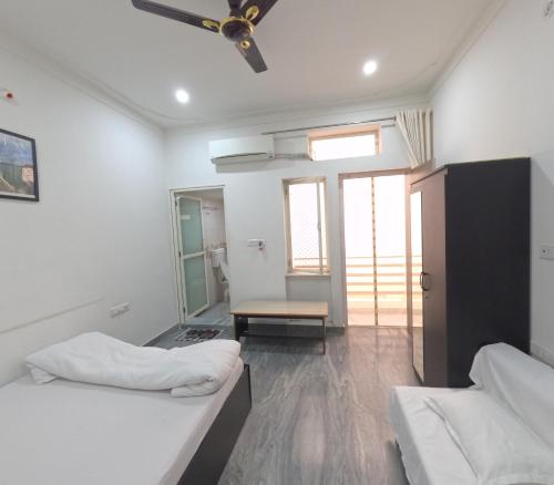 a bedroom with two beds and a ceiling fan at CHOUDHARY WHITE HOUSE Udaipur in Udaipur