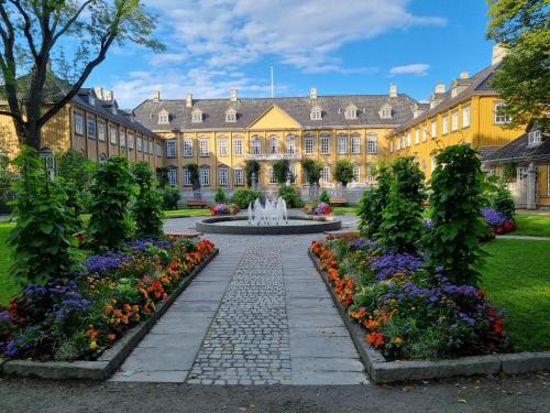 a building with a fountain and flowers in front of it at Brygga B&B Trondheim sentrum, privat rom i vårt hjem in Trondheim