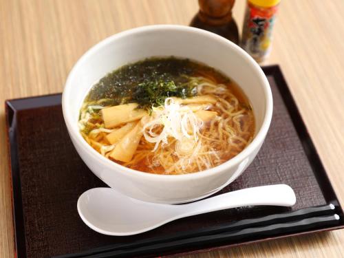 a bowl of soup on a black plate with a spoon at Dormy Inn Tsu in Tsu