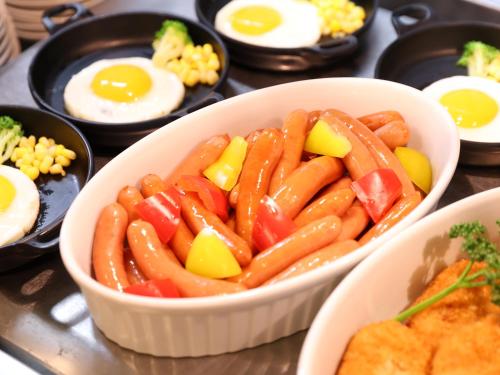 a bowl of sausage and eggs on a table at Dormy Inn Tsu in Tsu