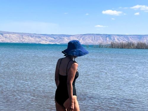 a woman wearing a blue hat standing in the water at הדירה- C Lake, סי כנרת in Migdal