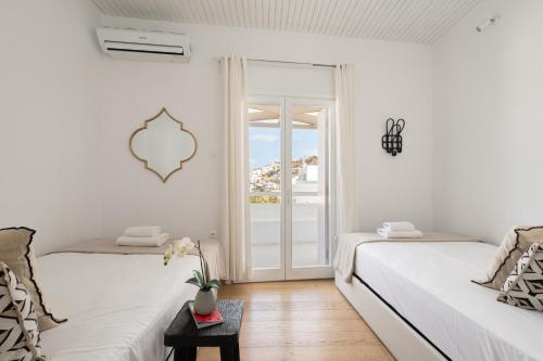 a white room with two beds and a sliding glass door at Sandy's House-Mykonos Town by Dival Properties in Mýkonos City