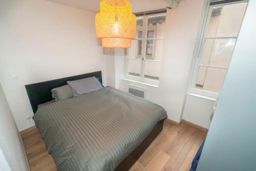 une chambre avec un lit dans une pièce avec deux fenêtres dans l'établissement Magnifique appartement 2 pièces en hyper centre, à Strasbourg