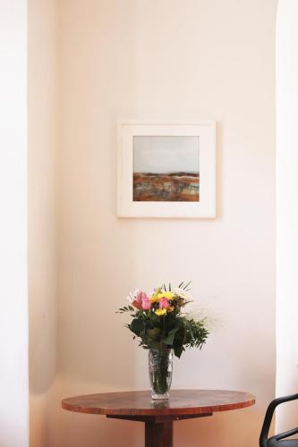 a vase of flowers on a table with a picture at Altstadt Idylle Bad Radkersburg in Bad Radkersburg