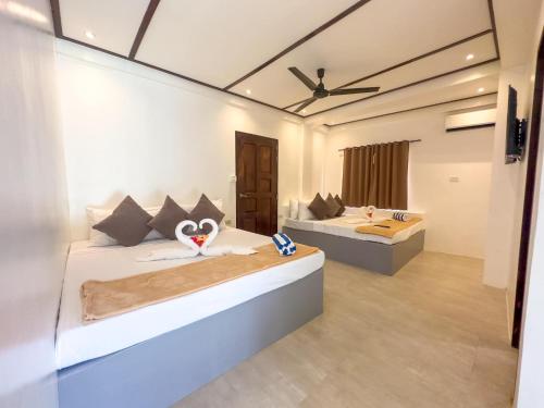 a bedroom with two beds and a ceiling fan at Orchids Villa Elnido in El Nido