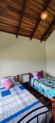 two beds in a room with wooden ceilings at Casa Arthémis - Guapiles in Guápiles