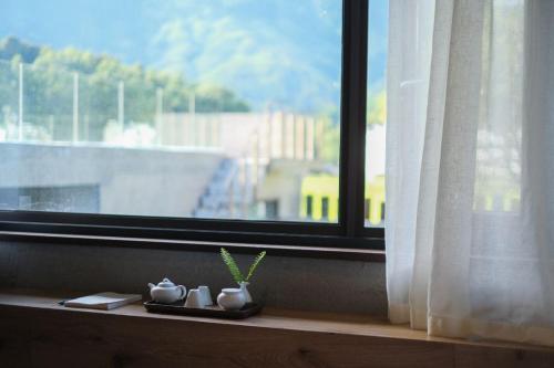 a window with white curtains and plants on a ledge at Wuyuan On The Bound Hotel-婺源水岸边民宿 in Jianlingjue