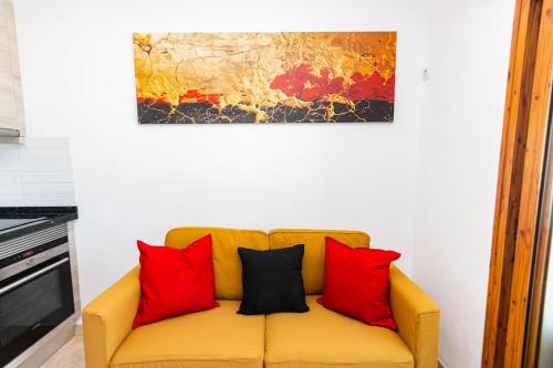 a yellow couch with red pillows and a painting on the wall at Almodo Suite Patalavaca in Patalavaca