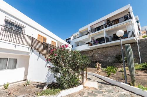a white apartment building with a fence and flowers at Almodo Suite Patalavaca in Patalavaca