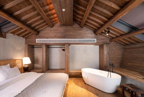 a bedroom with a bed and a bath tub at Wuyuan On The Bound Hotel-婺源水岸边民宿 in Jianlingjue