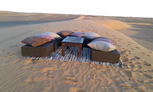 a group of pillows on a blanket in the desert at Khadija Desert Camp in Merzouga