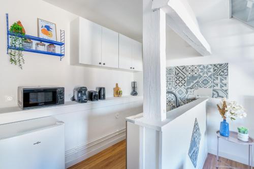 une cuisine avec des armoires blanches et un micro-ondes dans l'établissement Maisonnette Bleu Horizon avec jardin - 2min Gare - Serenito Homes, à Saint-Just-en-Chaussée