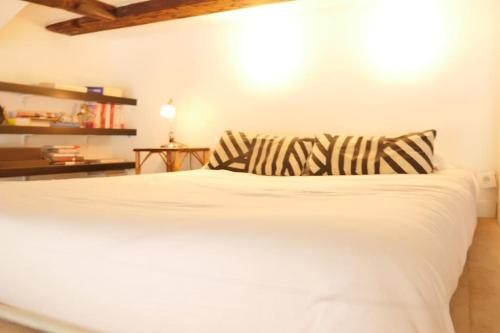 - un lit blanc avec des oreillers rayés dans une chambre dans l'établissement OPARADI 'Le vieux Lille' à deux pas des boutiques et restaurants, à Lille