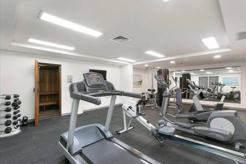 a gym with several tread machines in a room at Manly Vibes - fabulous design with gym, sauna, streaming, right opposite wharf & beach in Sydney